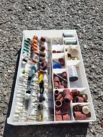 Tray with multiple compartments containing assorted sanding drums, wire brushes, polishing wheels, sanding belts, and small rotary tool bits and attachments.