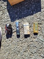 Four lighters placed on pavement; skull design, abstract pattern, engraved silver, and etched gold.