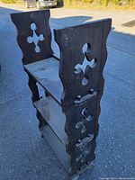 Side view of the wooden shelf showing decorative cut-out cross shapes and three shelves.