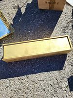 Closed wooden box showing the flat, smooth sliding lid on a rough outdoor surface.