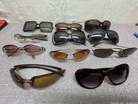 Overview showing all 11 pairs of sunglasses in various styles and colors together on a surface.