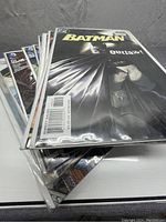Stack of Batman comic books in protective sleeves, first issue visible titled 'Batman Outlaw!'
