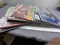 Stack of comic books laid on table showing variety of Justice League issues in plastic sleeves.