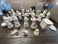 Wide shot showing the majority of Precious Moments figurines including children and angel figures on table
