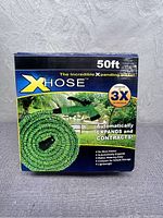 Front side of the Dap X-Hose box showing product name, hose image, capacity (50 ft), and features like automatic expansion, contraction, and kink resistance.