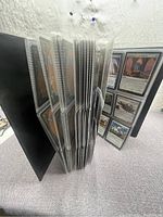 View of the open binder showing pages of plastic sleeves holding Magic: The Gathering cards, showing the card backs and some cards visible.