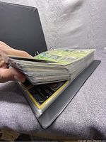 Gray three-ring binder thick with plastic card sleeves containing the Pokémon cards