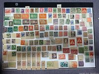 Top-down view of a large collection of vintage unused European stamps arranged in rows on a black backing.