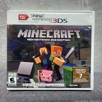 Front of the game case shows Minecraft New Nintendo 3DS Edition cover art with characters and title, rated E10+. Includes content packs mention.
