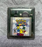 Front view of Pokemon Puzzle Challenge cartridge showing front label artwork with Pikachu and Pichu, ESRB rating E, and Nintendo branding under translucent gray cartridge shell.