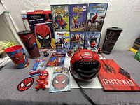 Photo showing multiple Spider-Man DVDs, mask clock, helmet, tumblers, patches, and figurines.