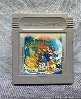 Front of Game Boy cartridge showing colorful Super Mario Land 2 label with Mario artwork and game title.
