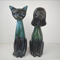 Front view of the tall Blue Mountain Pottery cat and dog statues showing dark green and black glaze and stylized facial features