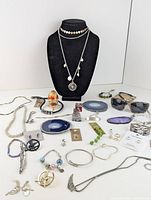 Photo of mixed costume jewelry assortment on black bust and flat surface showing necklaces, bracelets, rings, and decorative items