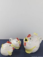 Front view of the three-piece chicken-themed teapot set including the teapot, sugar bowl, and creamer with visible painted details.