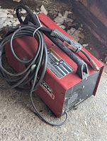 Side view of red Lincoln Electric welder with MIG gun cable coiled on top