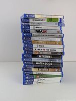Stack of PS4 game cases on white surface showing visible spines