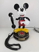 Front view of Mickey Mouse corded rotary dial telephone showing the character holding the handset and rotary dial on the base