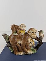 Side view of ceramic monkey family teapot showing three monkeys with bananas and detailed texture and colors.