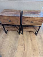 Front view of two identical nightstands showing wood grain tops, single drawers, metal legs, and lower shelves