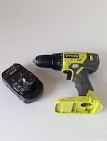 Ryobi cordless drill with 18V battery pack and separate battery pack included, placed on white surface.