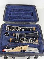 Clarinet parts in blue velvet-lined hard case with accessories including cloth and reed holder tube