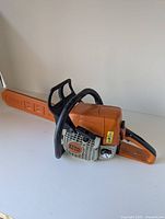 Full side view of orange Stihl chainsaw with bar scabbard