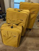 Three yellow SwissGear suitcases of varying sizes nested together, showing front zippered pockets and handles