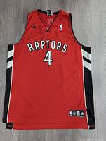 Full front view of red Toronto Raptors basketball jersey with number 4 and Adidas, NBA logos visible.