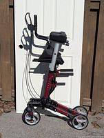 Photo showing a black and burgundy foldable walker with four wheels, adjustable height, hand brakes, a seat, and storage pouch.