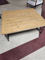 Top view of one wooden bench showing the light wood slats and black metal frame.