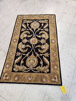 Photo showing the full area rug with floral pattern and golden-beige border on tiled floor.