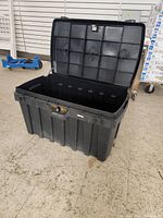 Large black plastic storage chest open to show interior, ribbed sides, and locking mechanism area.