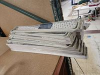 Stack of seventeen double curtain rods in original packaging piled on shelf