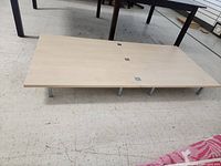 Foldable wooden platform in its folded state, showing the wood surface and metal legs.