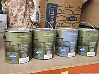 Four 1-gallon GreenSheen paint cans in violet color, displayed on a shelf with a box in the background.