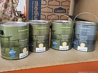 Four 1-gallon cans of Green Sheen Eco-Friendly Paint in yellow with metal handles and labels.