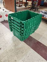 Side view of stacked green plastic totes showing the interlocking lid design