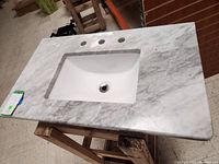 Marble countertop with three faucet holes and integrated rectangular white sink basin.