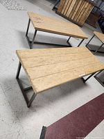 Two wooden benches with metal frames on a floor, one bench with writing on top and the other clean