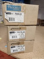 Photo showing three stacked boxes of Progress Lighting recessed lighting fixtures labeled with model numbers P8065-28 and P8176-28