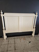 Front view of cream white wooden queen size headboard with vertical panel detailing and turned post finials