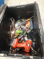 Photo of black plastic tote filled with various hand tools, bits, and an orange cordless drill.