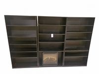 Front view of three black wooden bookcases side by side with an electric fireplace insert in the center unit.