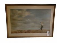 Framed print showing a boy running in a field holding a kite string, under a cloudy sky.