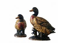 Photo showing front and side view of smaller and larger ceramic mallard duck figurines with detailed coloration and bases.