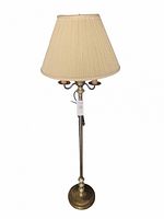 Brass floor lamp with a pleated cream fabric shade, three bulb sockets visible under the shade, round brass base, standing approximately 62 inches tall.