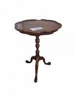 Side view of wooden small table showing scalloped top and carved pedestal base with three legs