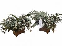 Photo showing two matching silk plant arrangements with green foliage in woven baskets on white background.