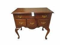 Clear front view of a small wooden chest of drawers with brass hardware; five drawers and curved legs visible.